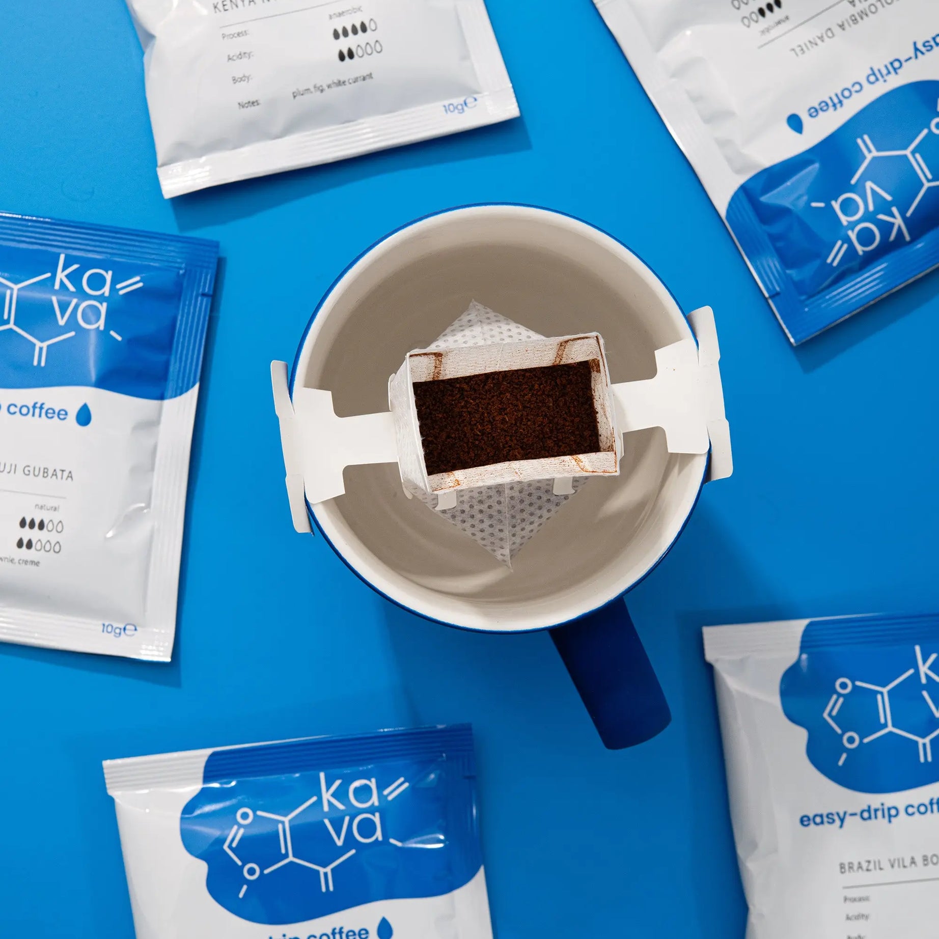 Une tasse de café accompagnée de quatre sachets de café variés sur un fond bleu