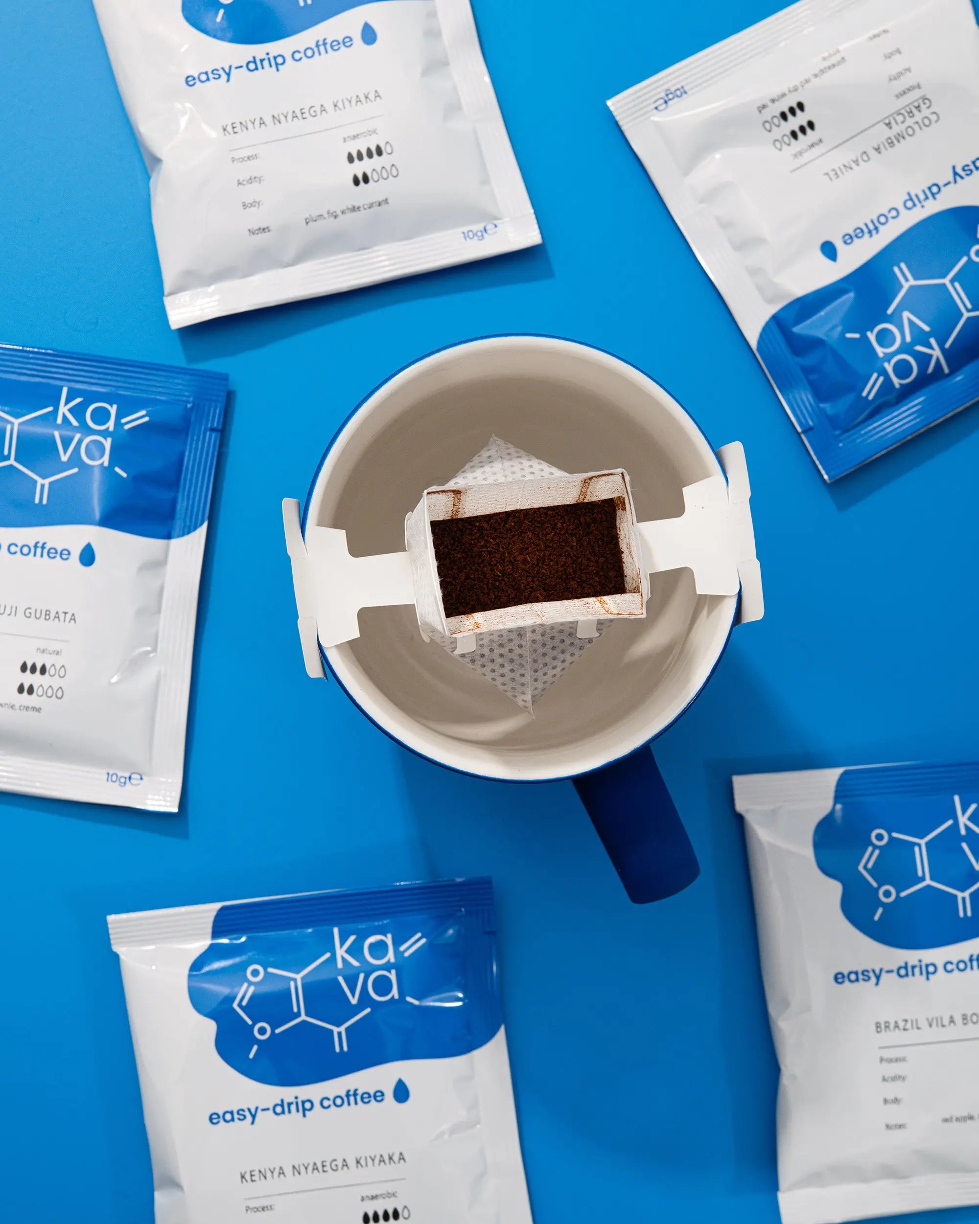 Une tasse de café accompagnée de quatre sachets de café variés sur un fond bleu